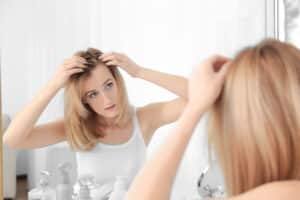 Woman examining her hair line after experiencing some hair loss
